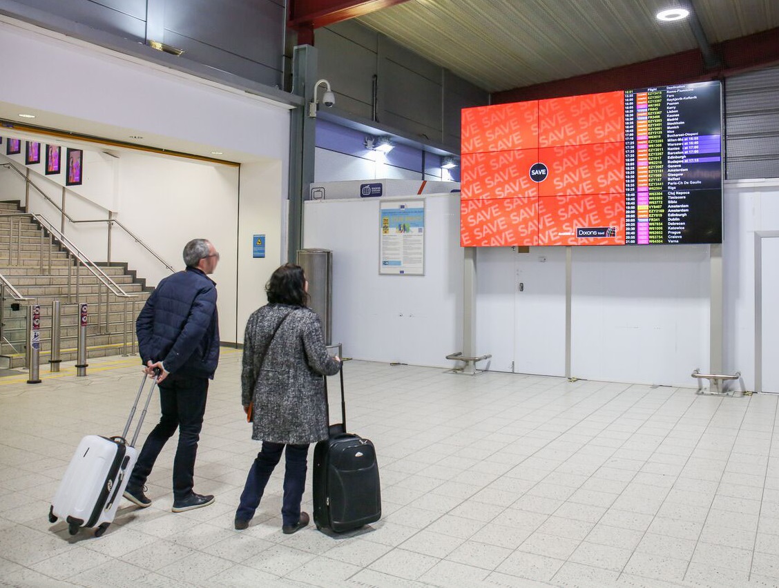 Passengers checking video wall with advertising and flight information